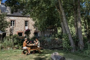 Un edificio de piedra rústico con un patio ajardinado.