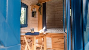 L’intérieur d’un chalet en bois comprend un coin repas, une petite fenêtre et un lit avec une literie à motifs.