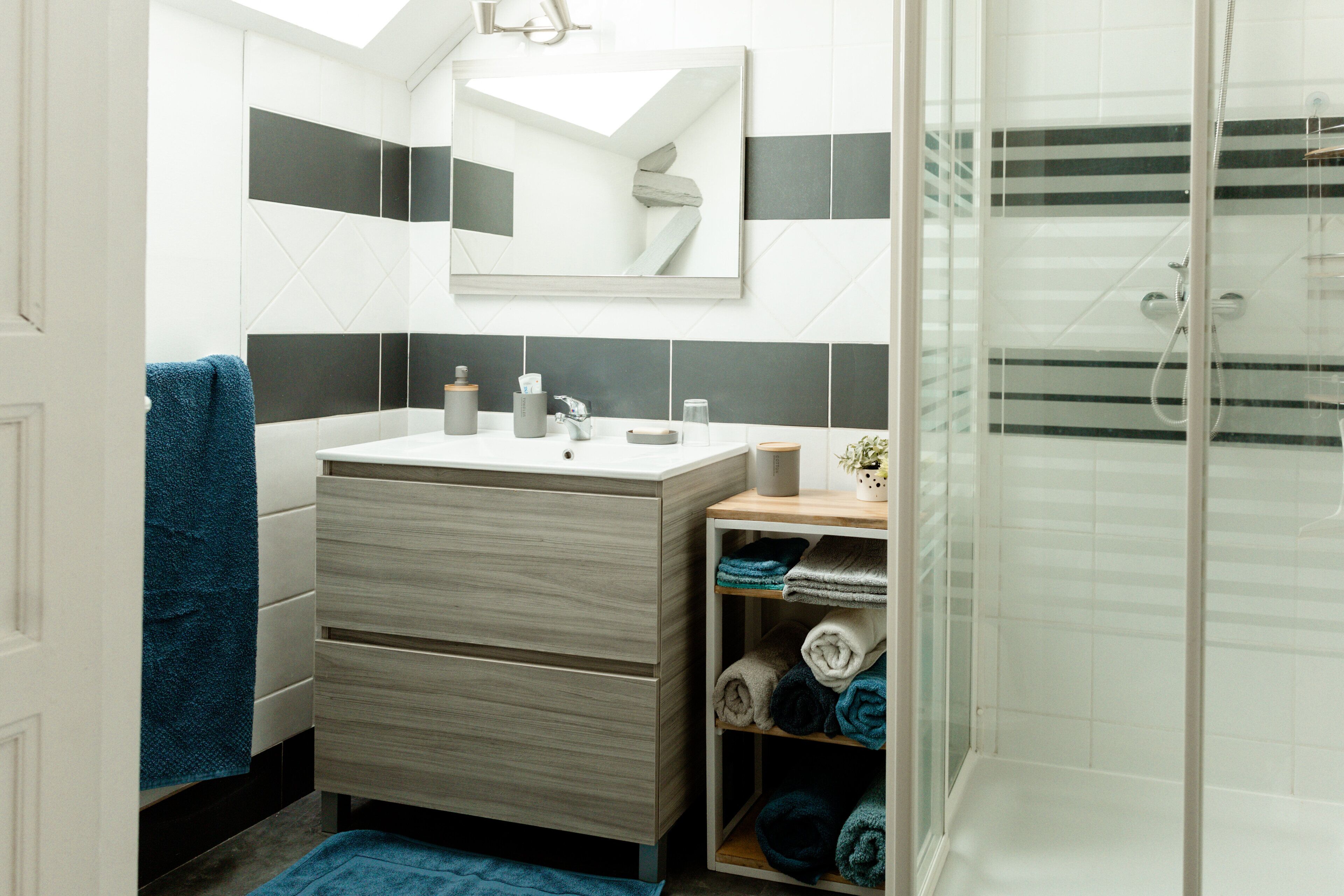 Un baño con lavamanos blanco, un espejo, toallero y zona de ducha.