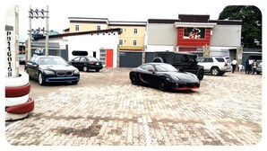 A parking area with multiple cars, including a black sports car and a silver sedan. - Nero Hotel (Lekki)