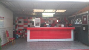 A red and white reception desk with a tiled wall behind it. - Nero Hotel (Lekki)