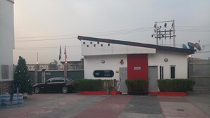 A building with a reception desk, a car parked in front, and a Christmas tree. - Nero Hotel (Lekki)
