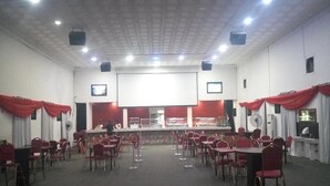 A conference room with a stage, tables, and chairs arranged for an event. - Nero Hotel (Lekki)