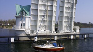 A boat docked at a pier with a large white building in the background.