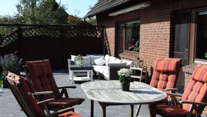 An outdoor patio area with a round wooden table, cushioned chairs, and a sofa.
