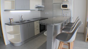A compact kitchen with a sink, countertop, and bar stools. - Pi Sunyer 4 1B - One Bedroom Apartment, Sleeps 4 (Roses)