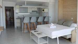 A compact hotel room with a bed, a small kitchenette, and a seating area with stools. - Pi Sunyer 4 1B - One Bedroom Apartment, Sleeps 4 (Roses)
