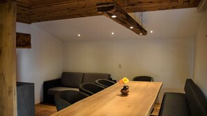 Un intérieur moderne avec une table à manger en bois, des sièges noirs recouverts de tissu et un éclairage encastré.