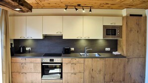 Une cuisine moderne avec des meubles en bois, un four encastré, un four à micro-ondes et un évier.
