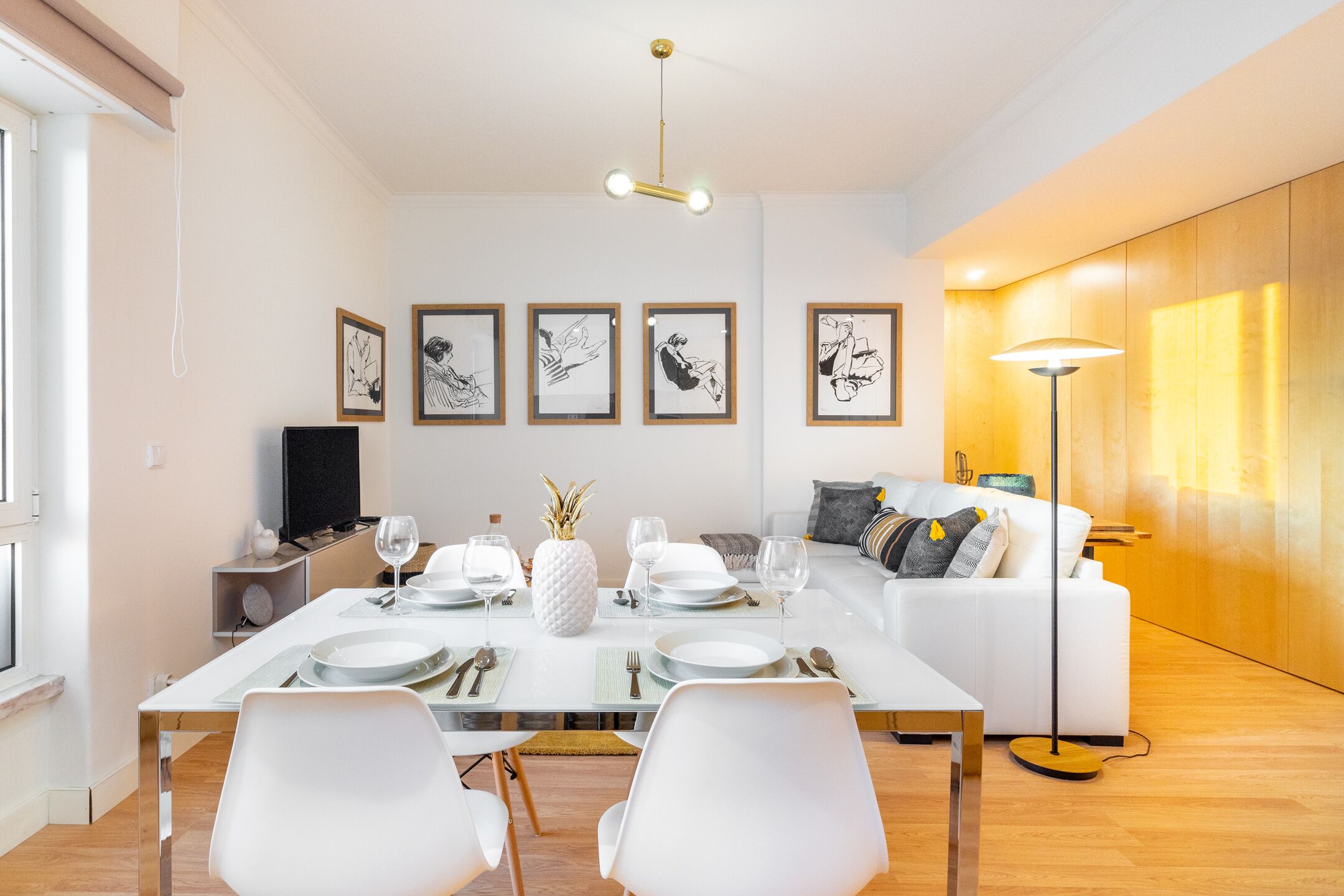 A modern dining area with a glass table, white chairs, and a white sofa in the background.