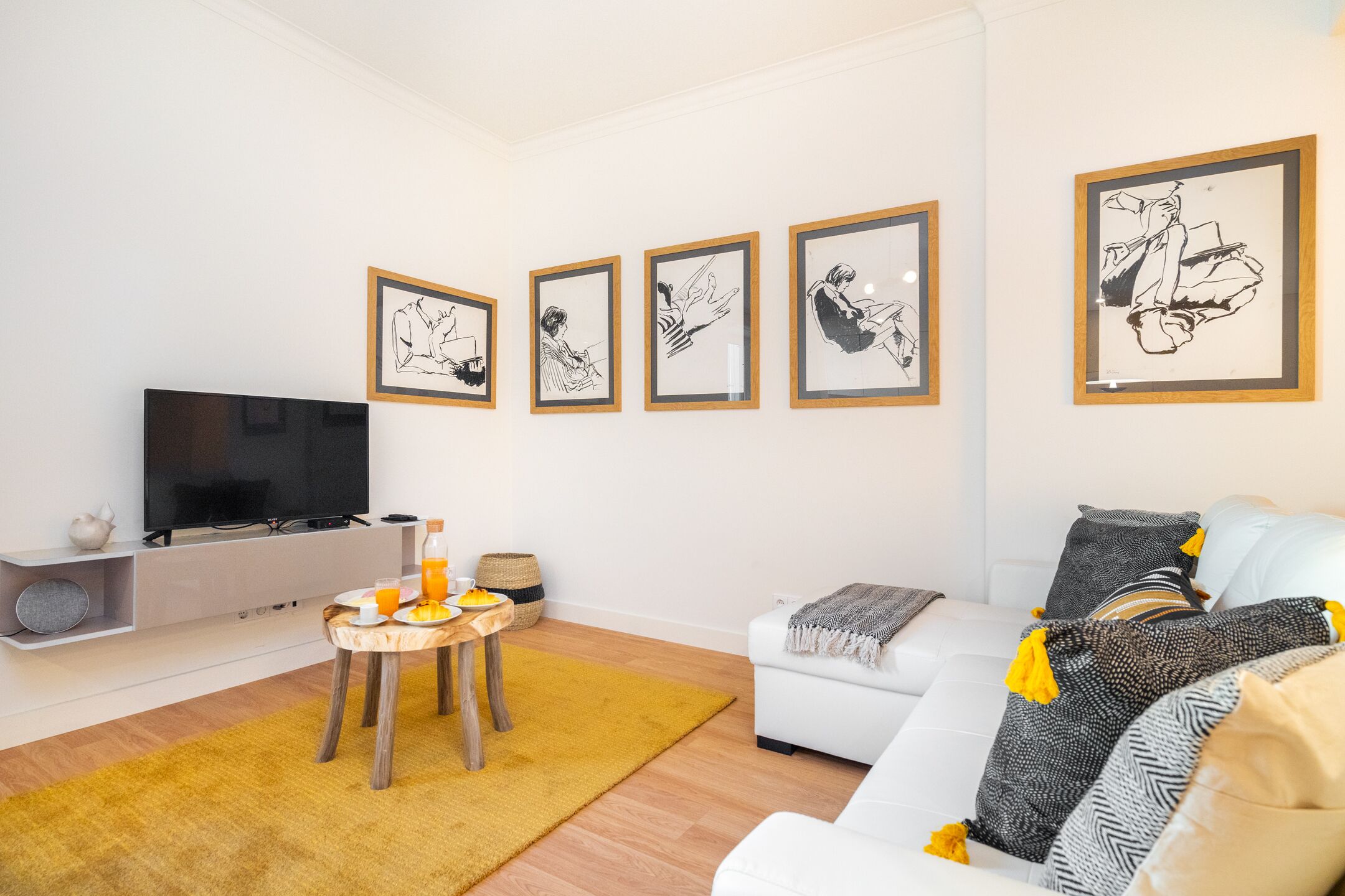 Un soggiorno moderno con una TV a schermo piatto, un tavolino da caffè e un divano. Quattro opere d'arte appese alla parete.
