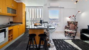 Una cocina moderna con una isla central, taburetes de bar y un amplio ventanal con vistas a la ciudad.