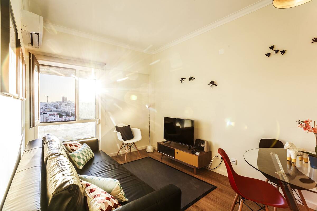 Ein modernes Wohnzimmer mit Sofa, Fernseher und Essbereich.