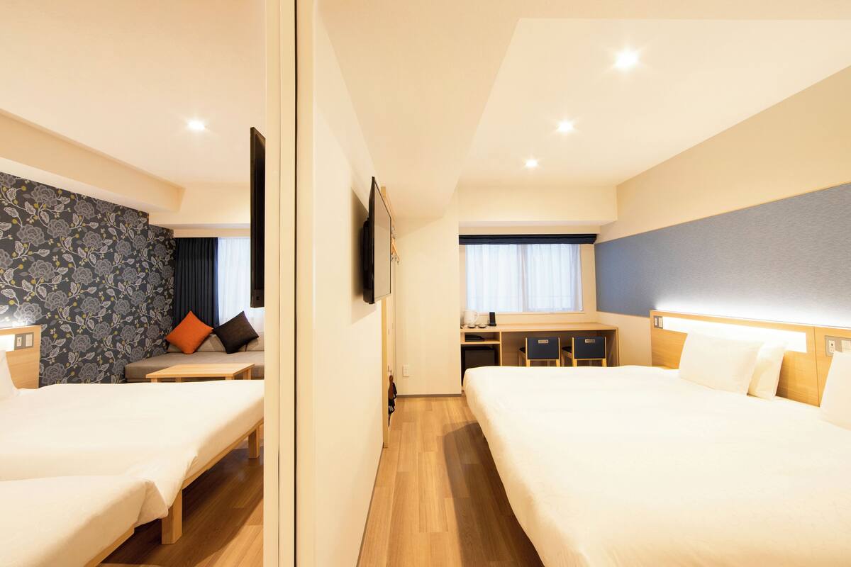 A hotel room with two beds, a desk, and a seating area.
