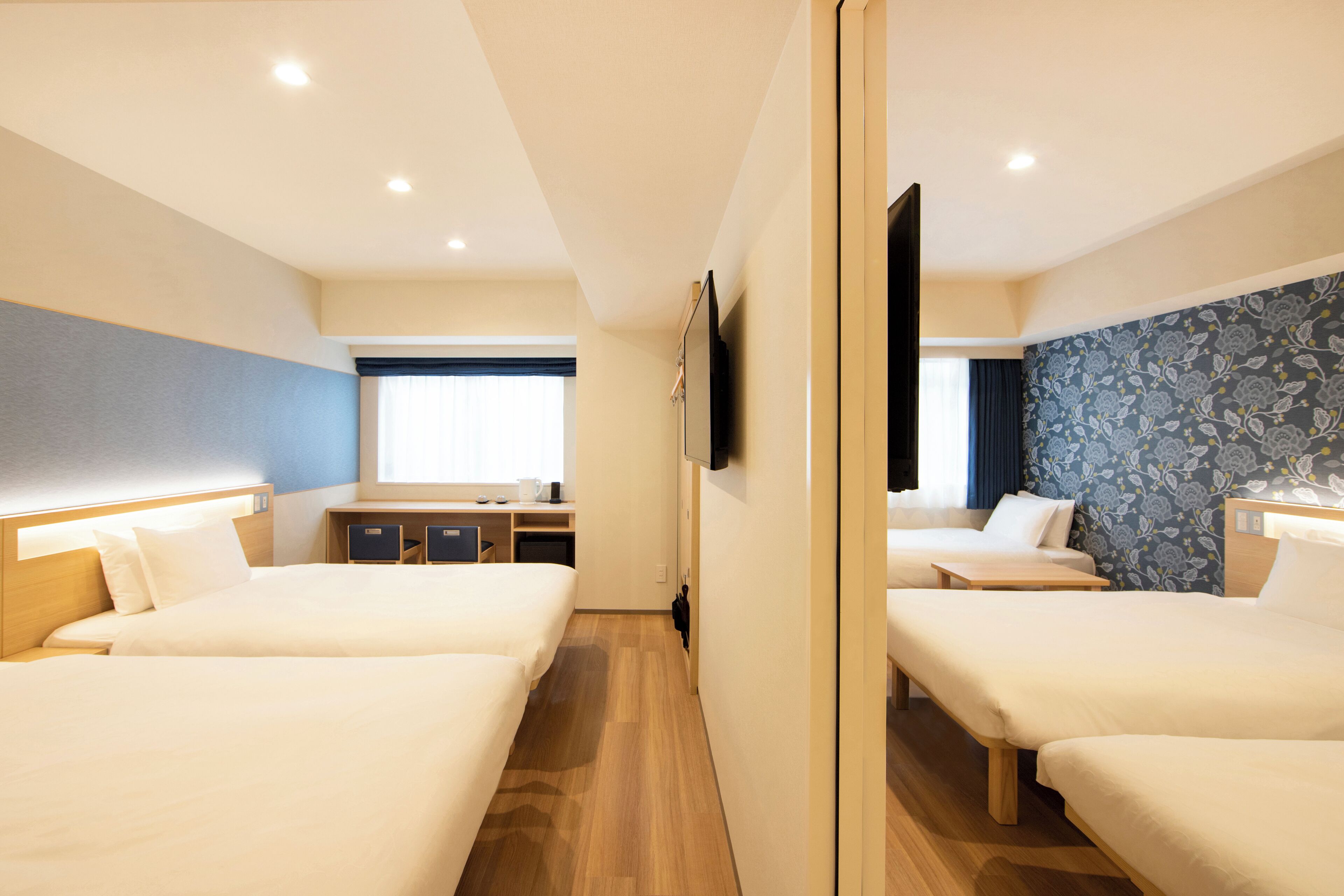 Habitación de hotel con tres camas, un escritorio y un televisor.