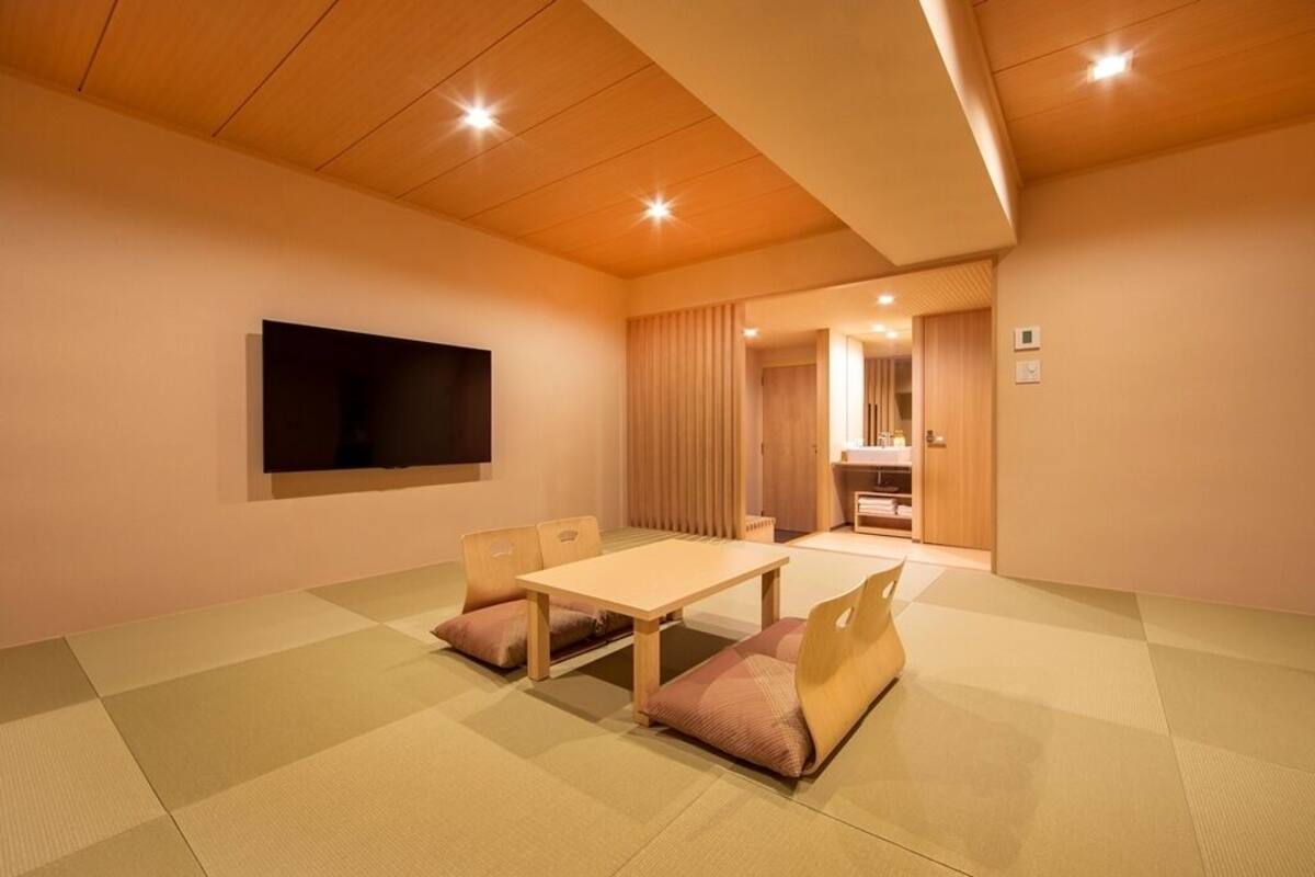 A room with tatami mats, a wooden table, and chairs.