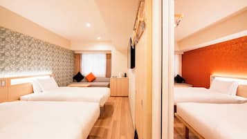 Una habitación de hotel con dos camas, un sofá, un televisor y una pequeña kitchenette.