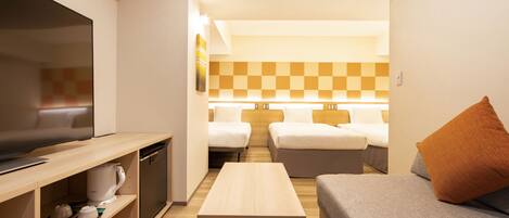 Habitación de hotel compacta con televisión, kitchenette, dos camas y una pequeña mesa.