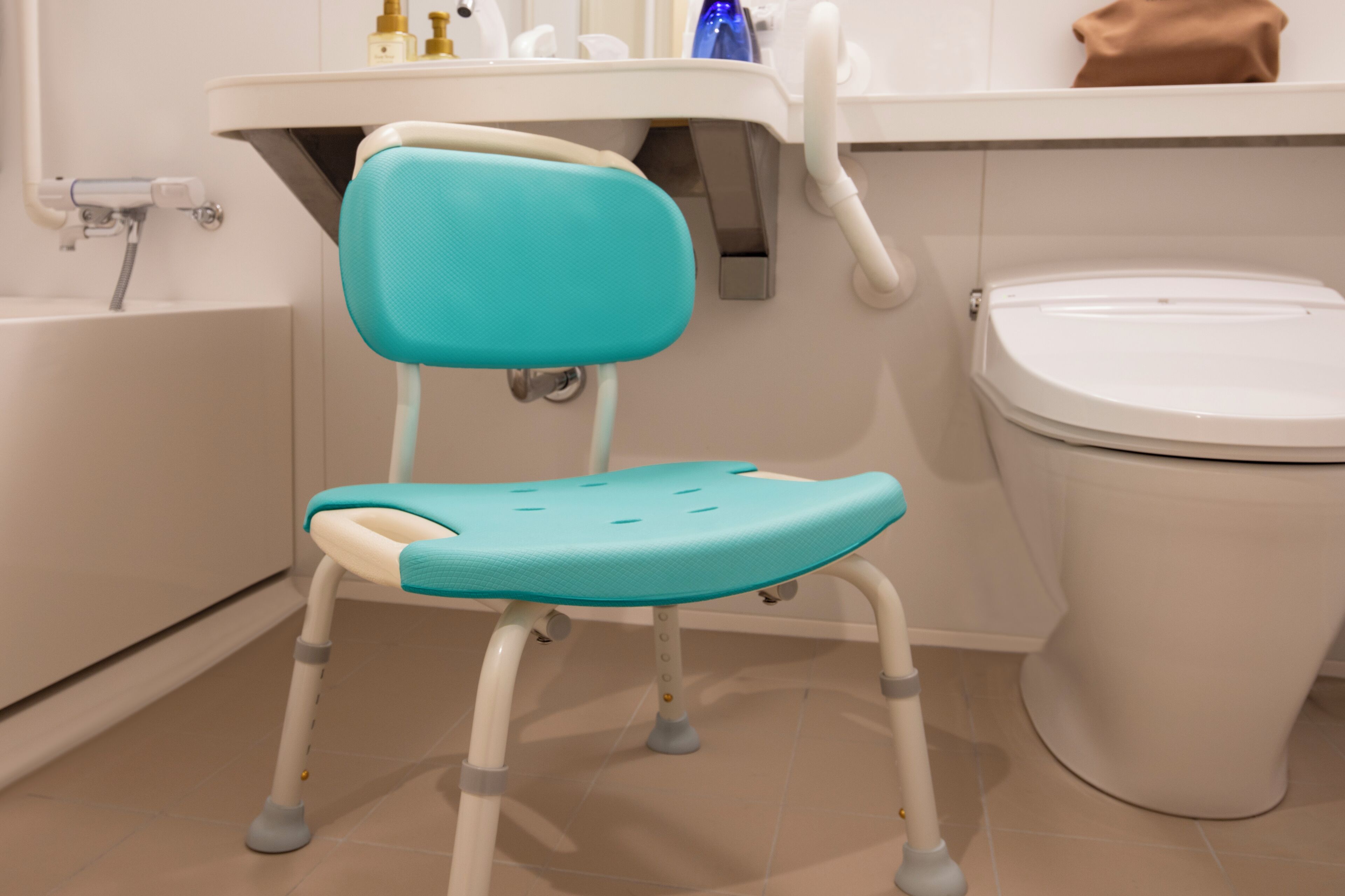 A bathroom with a turquoise child’s potty chair, a white toilet, and a bathtub.