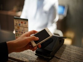 A hand holding a smartphone over a payment terminal.