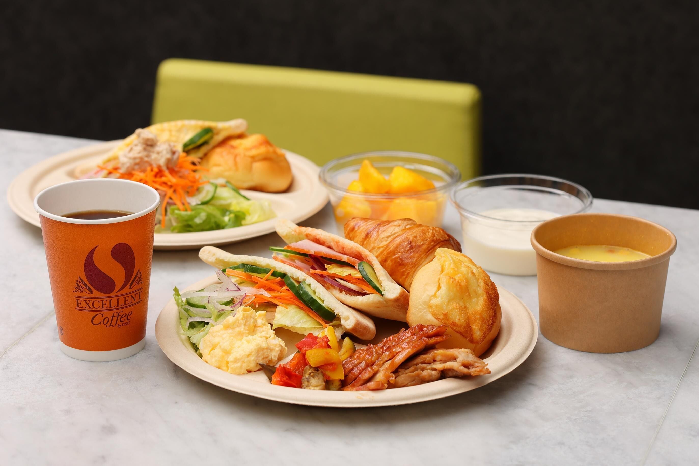 A meal with a croissant, salad, and a cup of coffee on a table.