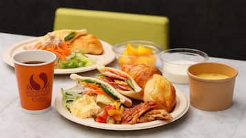 A meal with a croissant, salad, and a cup of coffee on a table.