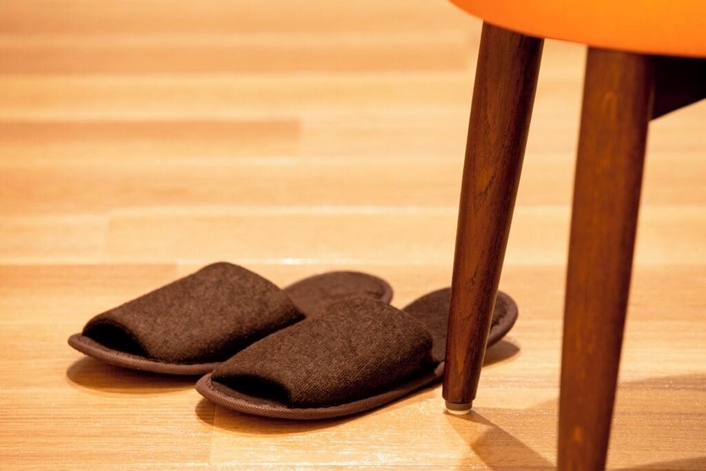 A pair of brown slippers on a wooden floor.