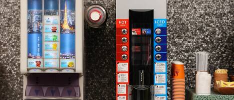 Un distributeur automatique de café proposant des options de café chaud et de café glacé, doté d’un écran affichant le menu et d’un présentoir rempli de gobelets jetables.