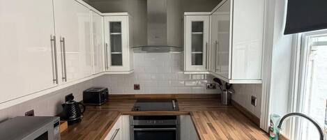 A compact kitchen with a washing machine, a microwave, a toaster, and a sink.