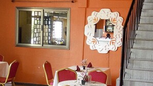 Un comedor con una mesa dispuesta para cuatro personas, sillas tapizadas en rojo y un elemento decorativo en la pared.