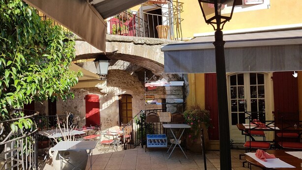 Un pati amb seients exteriors, un arc de pedra i un rètol d'hotel.