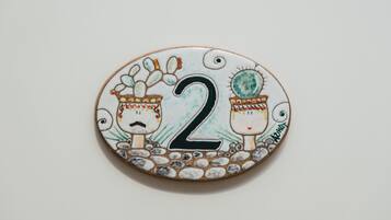 Un objeto circular con el número 2 y dos figuras, posiblemente indicando un número de habitación o un adorno.