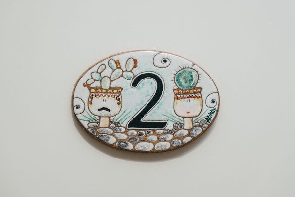 Un objeto circular con el número 2 y dos figuras, posiblemente indicando un número de habitación o un adorno.