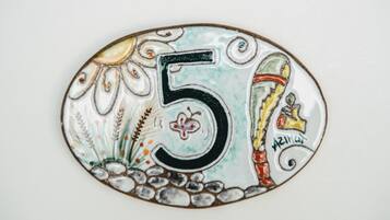 Placa decorativa de cerâmica com o número 5, com ilustração de campo de trigo e um pássaro.