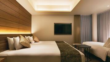 A hotel room with a large bed, a smaller bed, a desk, and a TV on the wall.