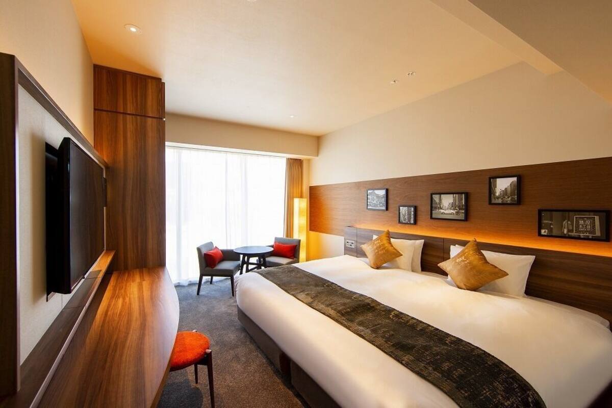 Hotellihuone, jossa on sänky, televisio, työpöytä ja tuoli.