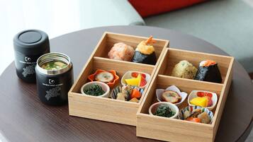 A wooden bento box with various sushi and side dishes on a table.