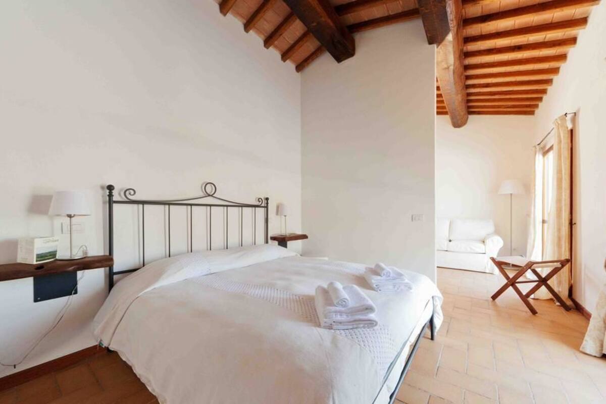 Un dormitorio con cama, mesitas de noche, lámpara y techo de madera.