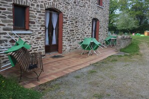 A stone building with a brick pathway leading to outdoor seating. - Maison d'hôtes La Lavandière (La Chapelle-au-Riboul)