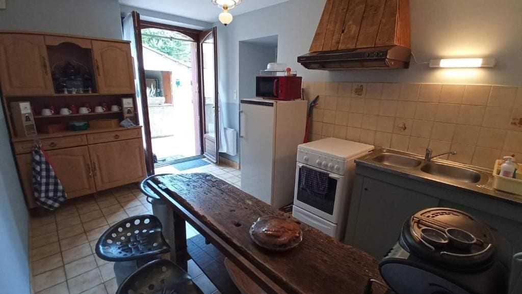 Eine kleine Küche mit Holztisch, Mikrowelle, Herd und Spüle.