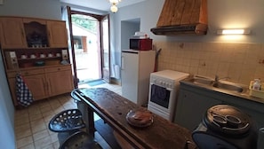 A compact kitchen with a wooden table, a microwave, a stove, and a sink.