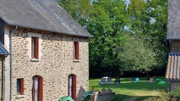 A stone building with a gravel path leading to a grassy area with outdoor seating.
