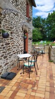 Un edificio de piedra con un patio que tiene mobiliario exterior y macetas colgantes.
