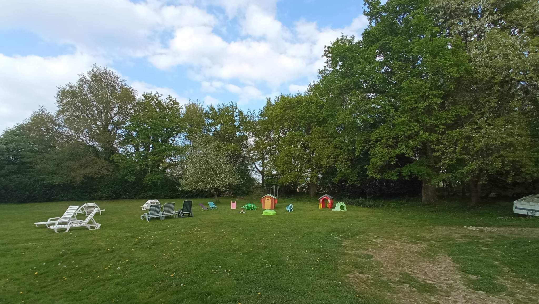 A grassy outdoor area with several play structures, including a swing set and small houses.