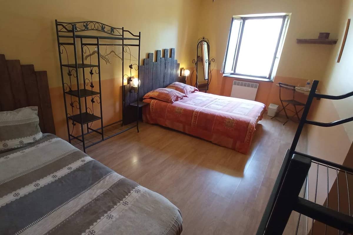 A bedroom with a bed, a chair, a wardrobe, and a window.