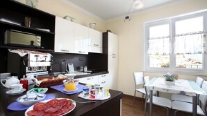 Une cuisine moderne avec des meubles blancs, un plan de travail noir et un coin repas comprenant une table et des chaises.