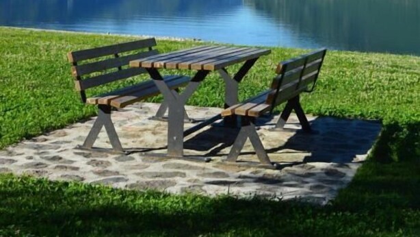Un banc au bord d’un lac, avec des montagnes en arrière-plan.