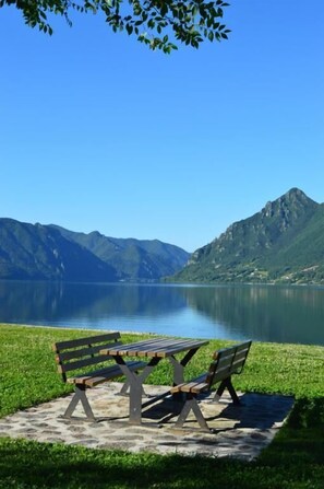 Un banco junto a un lago, con montañas al fondo.