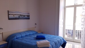 A bedroom with a bed, a painting, and a window with a view of a building. - B&B Napul'è (Naples)