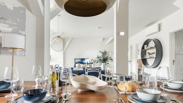 Un coin repas avec une table en bois mise pour un repas, comprenant des assiettes, des bols et des couverts.